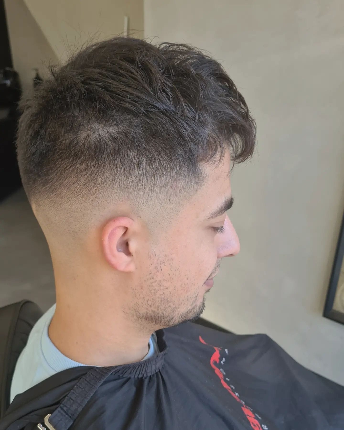 Donker zijwaarts gestyled cropkapsel met een gelijkmatige mid fade